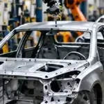 Editorial image showing robotic arms assembling an automobile body.